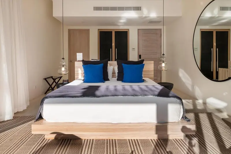 Une chambre lumineuse avec un grand lit et un miroir rond.