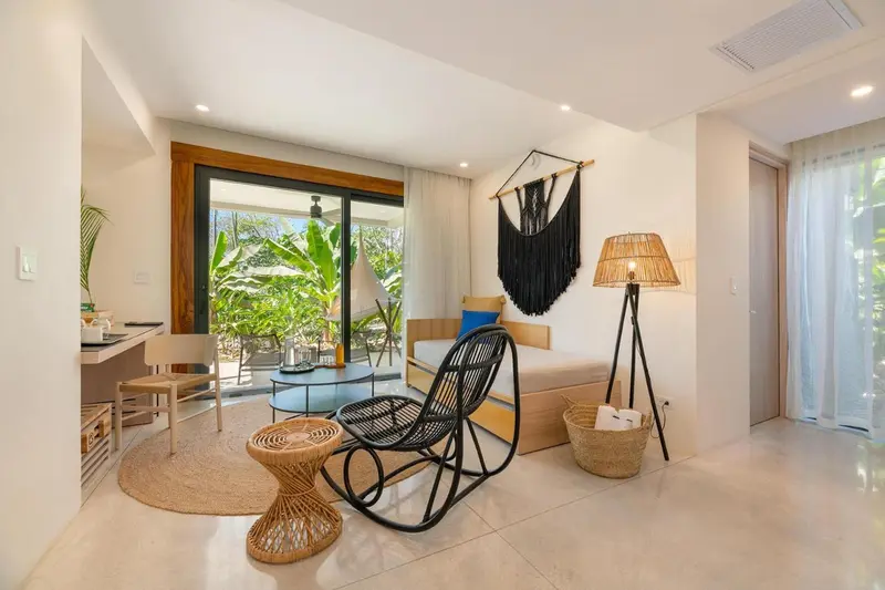 Espace de vie lumineux avec décoration ethnique et accès à une terrasse.