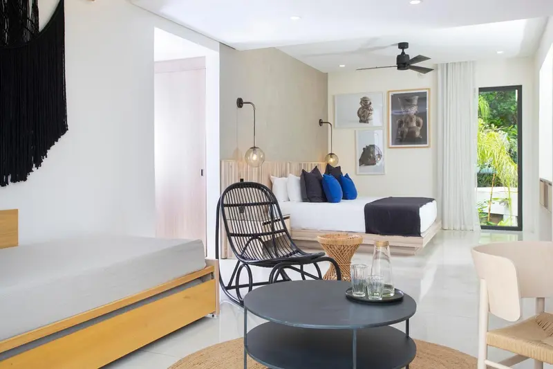 Une chambre lumineuse avec un lit double et un coin salon.