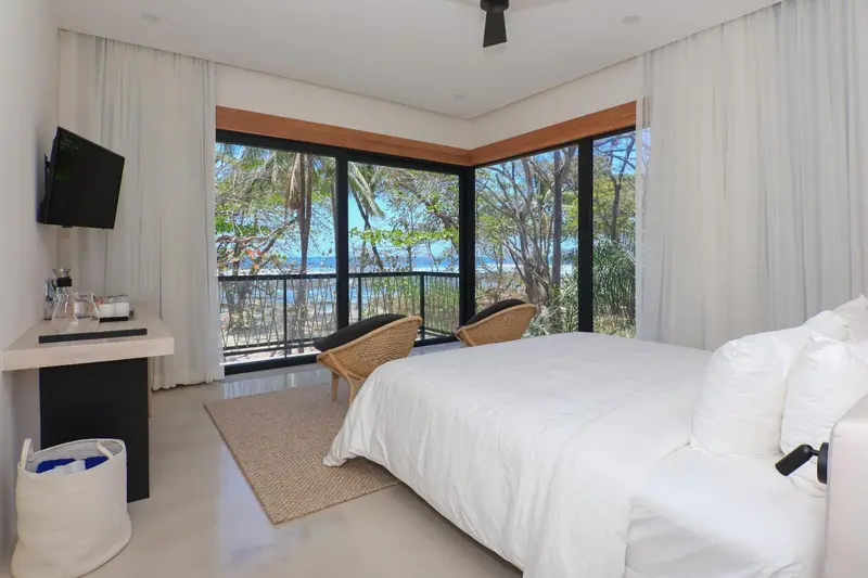 Une chambre lumineuse avec un grand lit et une vue sur la végétation.