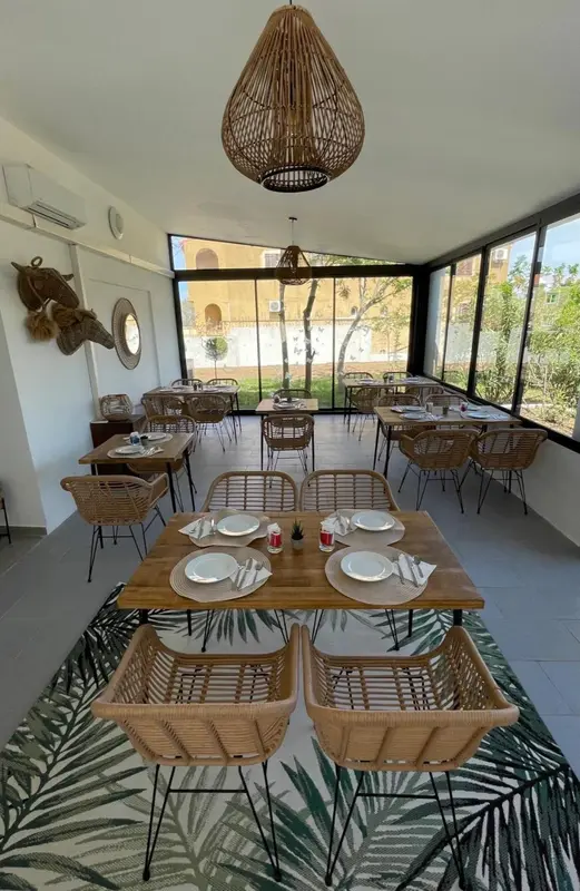 Une salle à manger lumineuse avec des tables dressées et une décoration naturelle.