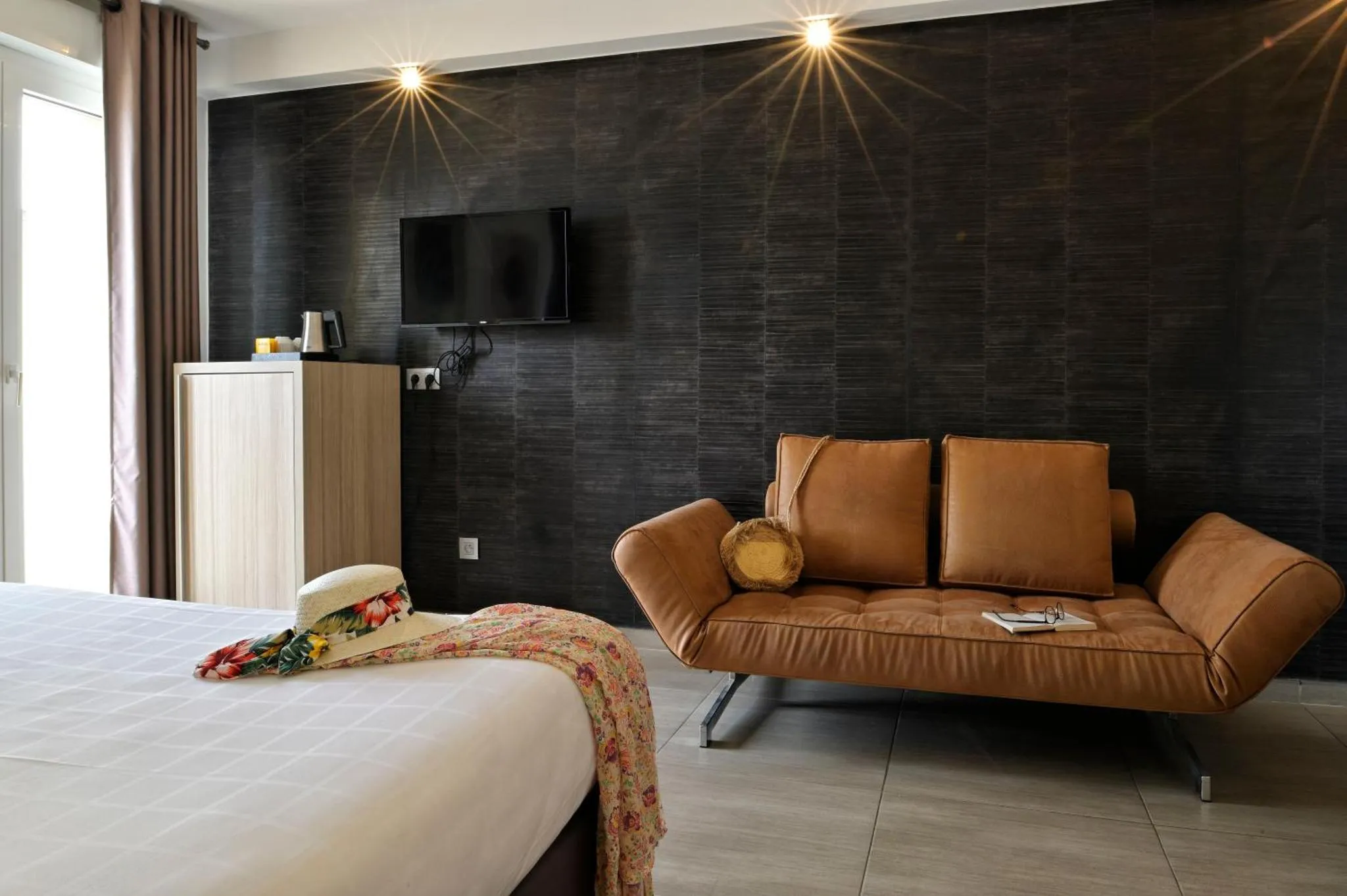 Espace de détente avec canapé en cuir et lit recouvert d'un plaid.