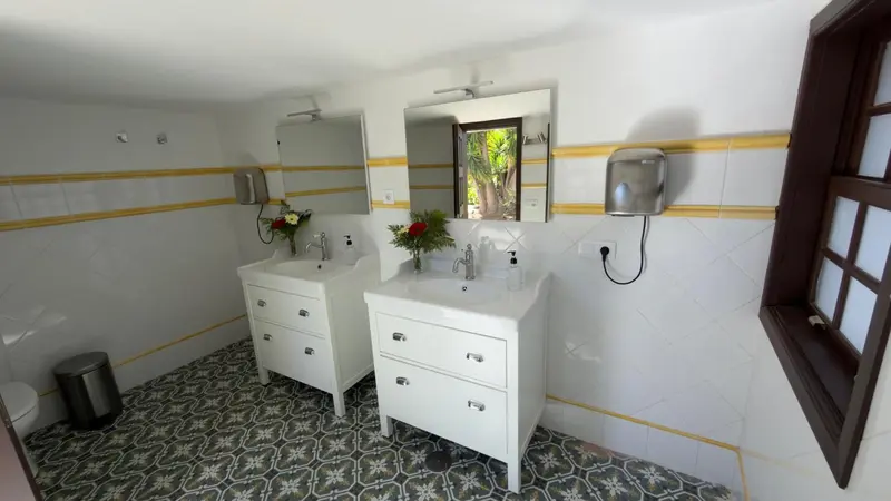 Une salle de bain lumineuse avec deux lavabos et un sol carrelé.