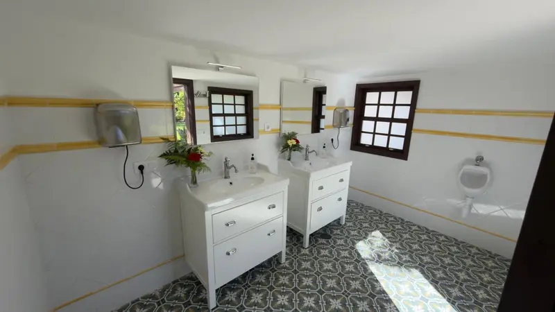 Une salle de bain lumineuse avec deux vasques et un carrelage au sol.