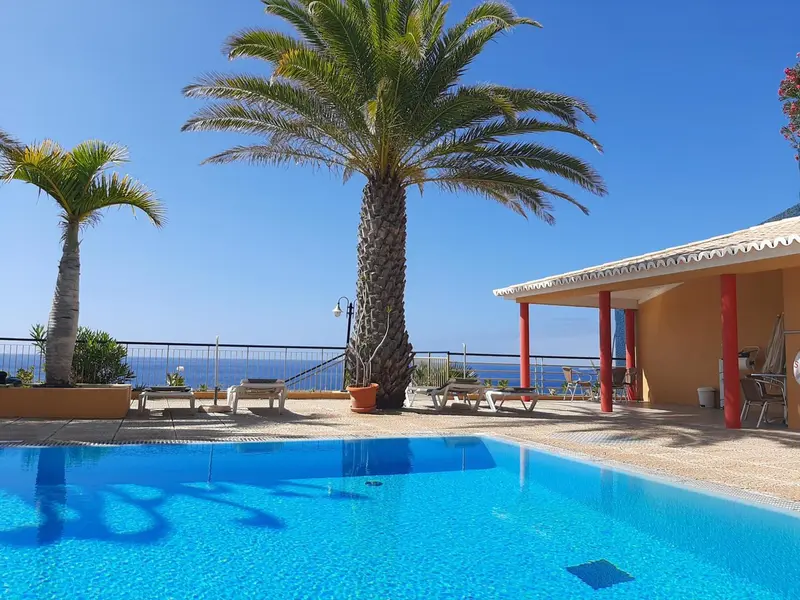 Terrasse avec piscine et vue sur la mer sous un ciel bleu.