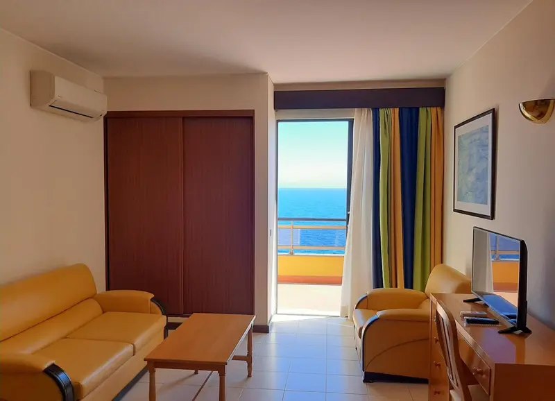 Espace de séjour lumineux avec canapés et vue sur la mer.
