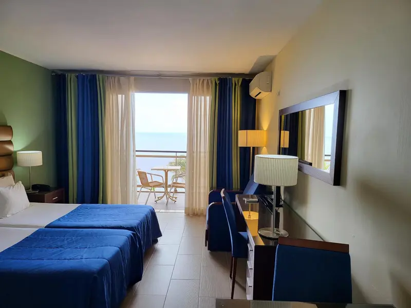 Chambre lumineuse avec vue sur la mer depuis une baie vitrée.