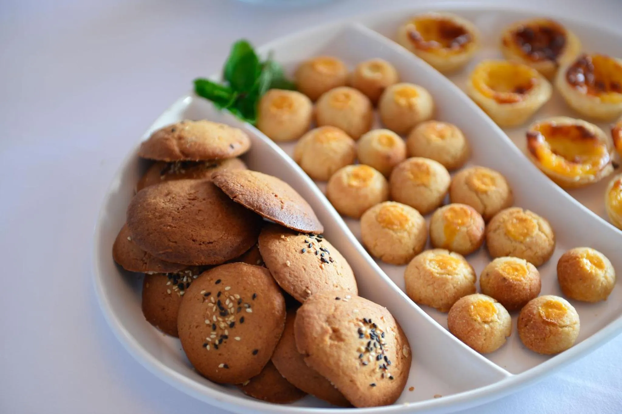 Assortiment de pâtisseries et de biscuits présentés sur un plat blanc.