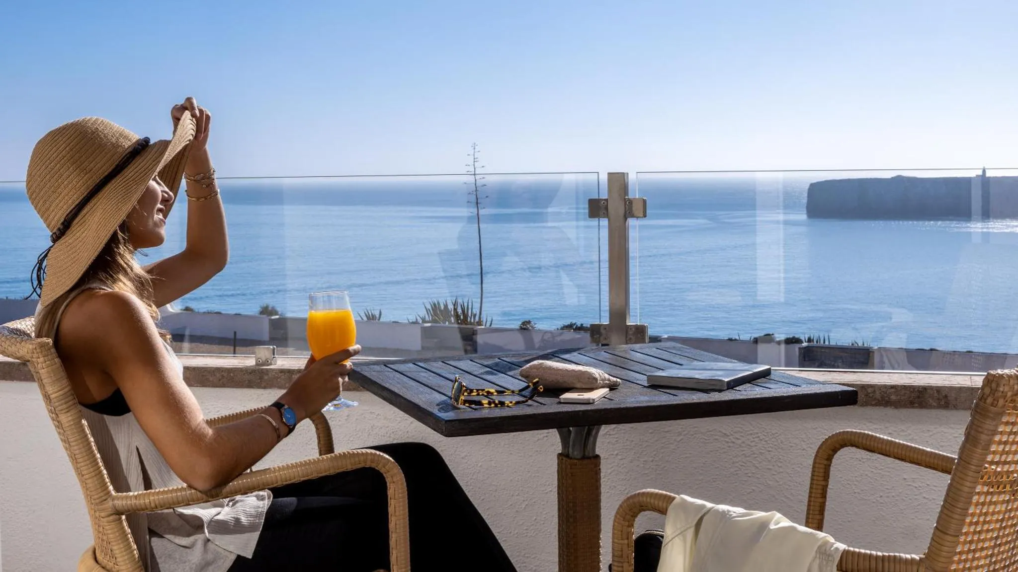 Une femme se détend sur une terrasse avec vue sur la mer.