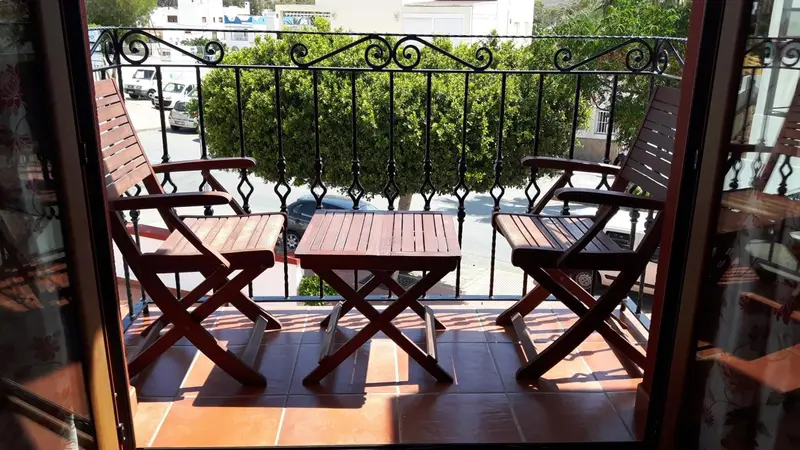 Deux fauteuils et une petite table en bois sur un balcon carrelé.