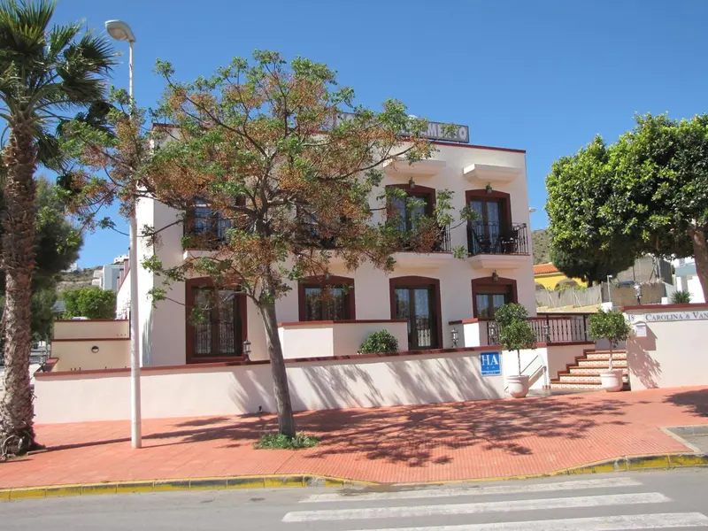 Façade d'un bâtiment blanc à deux étages avec des balcons et des arbres devant.