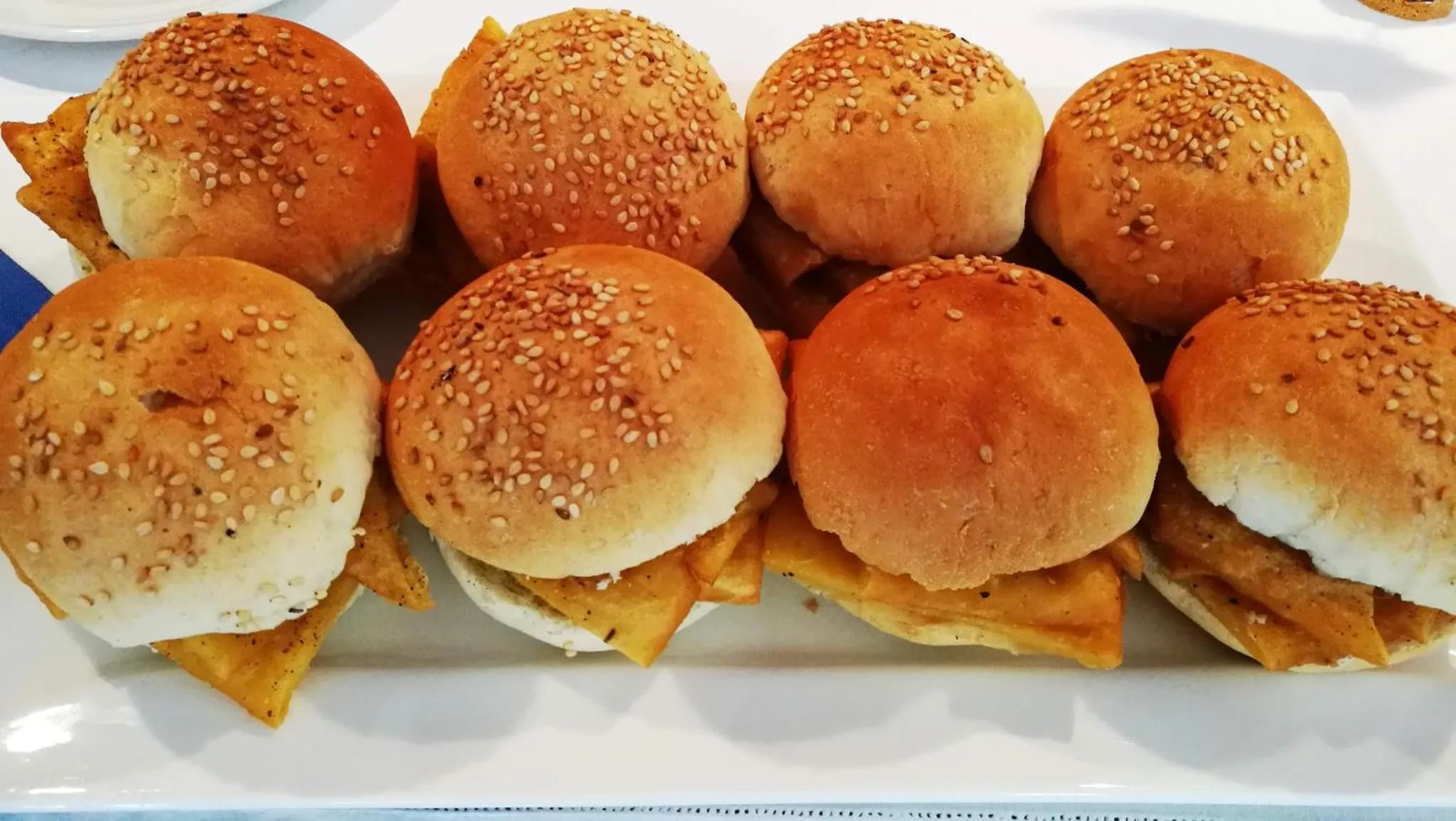 Assortiment de petits pains garnis servis sur un plat blanc.