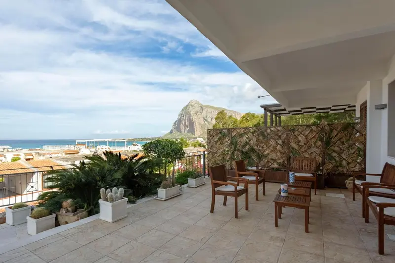 Terrasse carrelée avec mobilier de jardin et vue sur la mer.