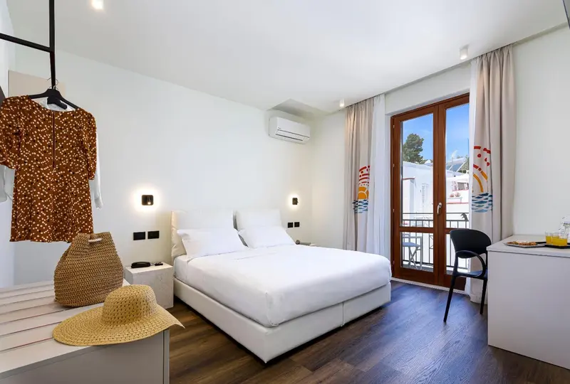 Une chambre lumineuse avec un grand lit et un accès à un balcon.