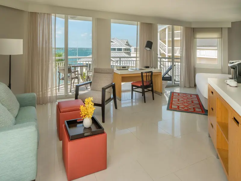 Espace de vie lumineux avec canapé, bureau et vue sur la mer.