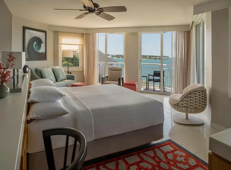 Une vue d'ensemble d'une chambre à coucher avec un lit double, des tables de chevet et un balcon donnant sur la mer.
