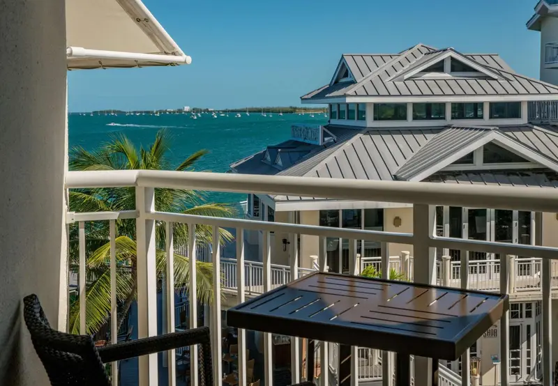 Vue d'une terrasse avec une rambarde blanche et des bâtiments en arrière-plan.