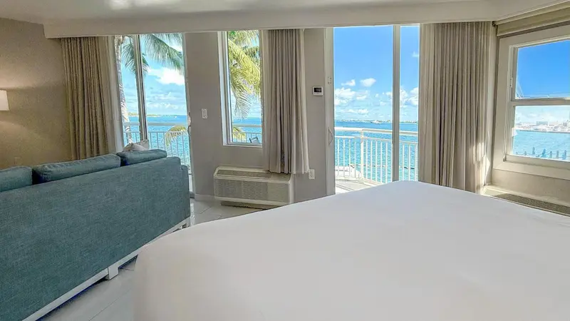 Une chambre lumineuse avec un grand lit et un canapé donnant sur une vue sur la mer.