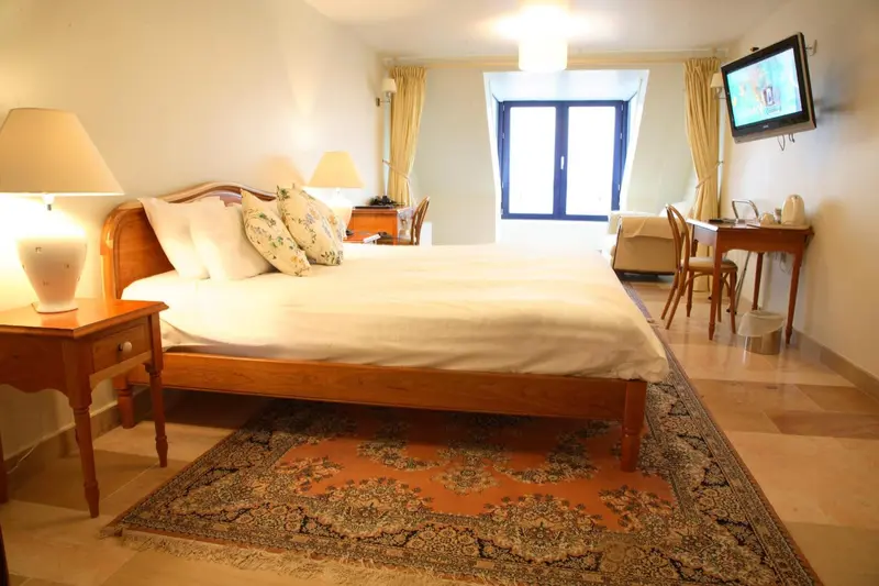 Une chambre lumineuse avec un grand lit et un bureau.
