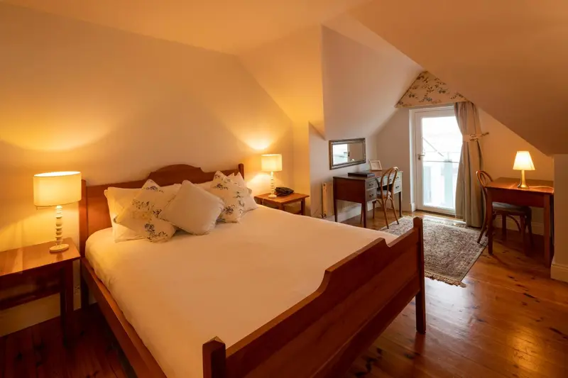 Une chambre lumineuse avec un grand lit et un bureau près d'une fenêtre.