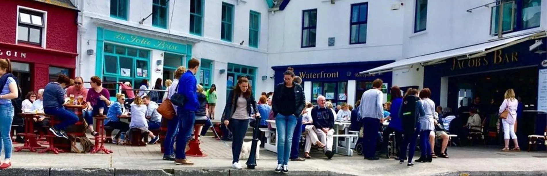 Une terrasse de café animée avec des clients assis à des tables en extérieur.