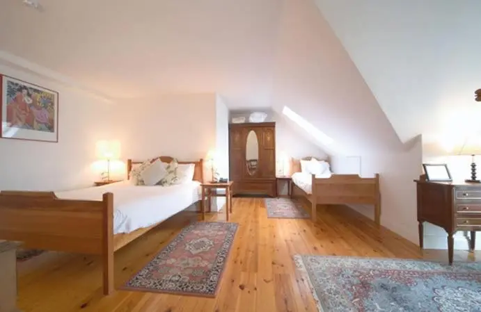 Une chambre lumineuse avec deux lits simples et un parquet en bois.