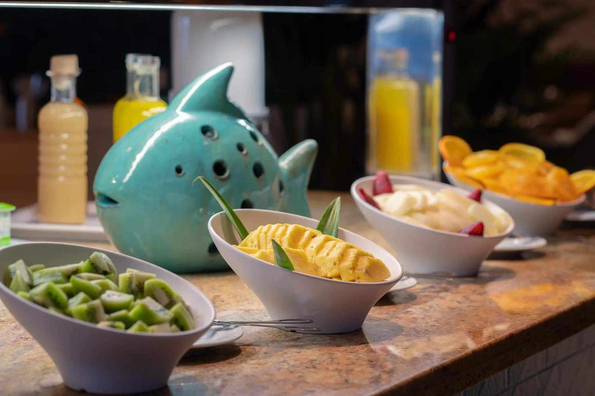Une variété de fruits frais et de jus sont présentés dans des bols et des carafes sur un comptoir.