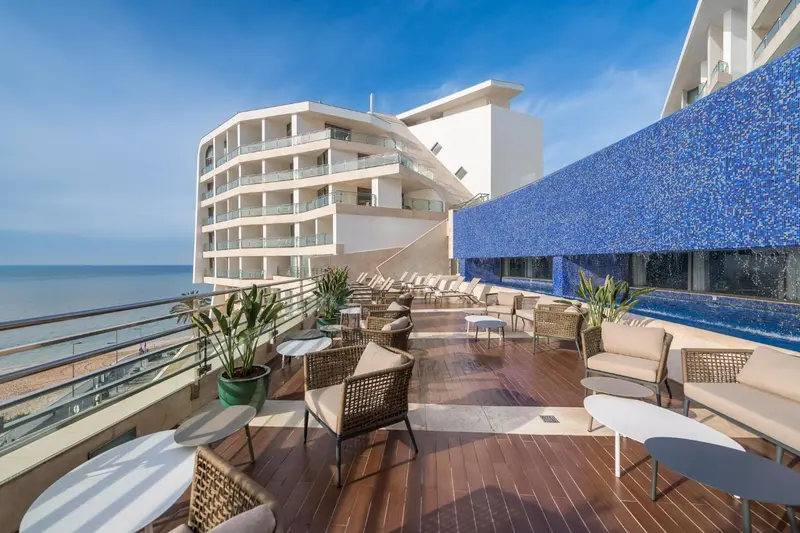 Terrasse aménagée avec mobilier de jardin et piscine à débordement.
