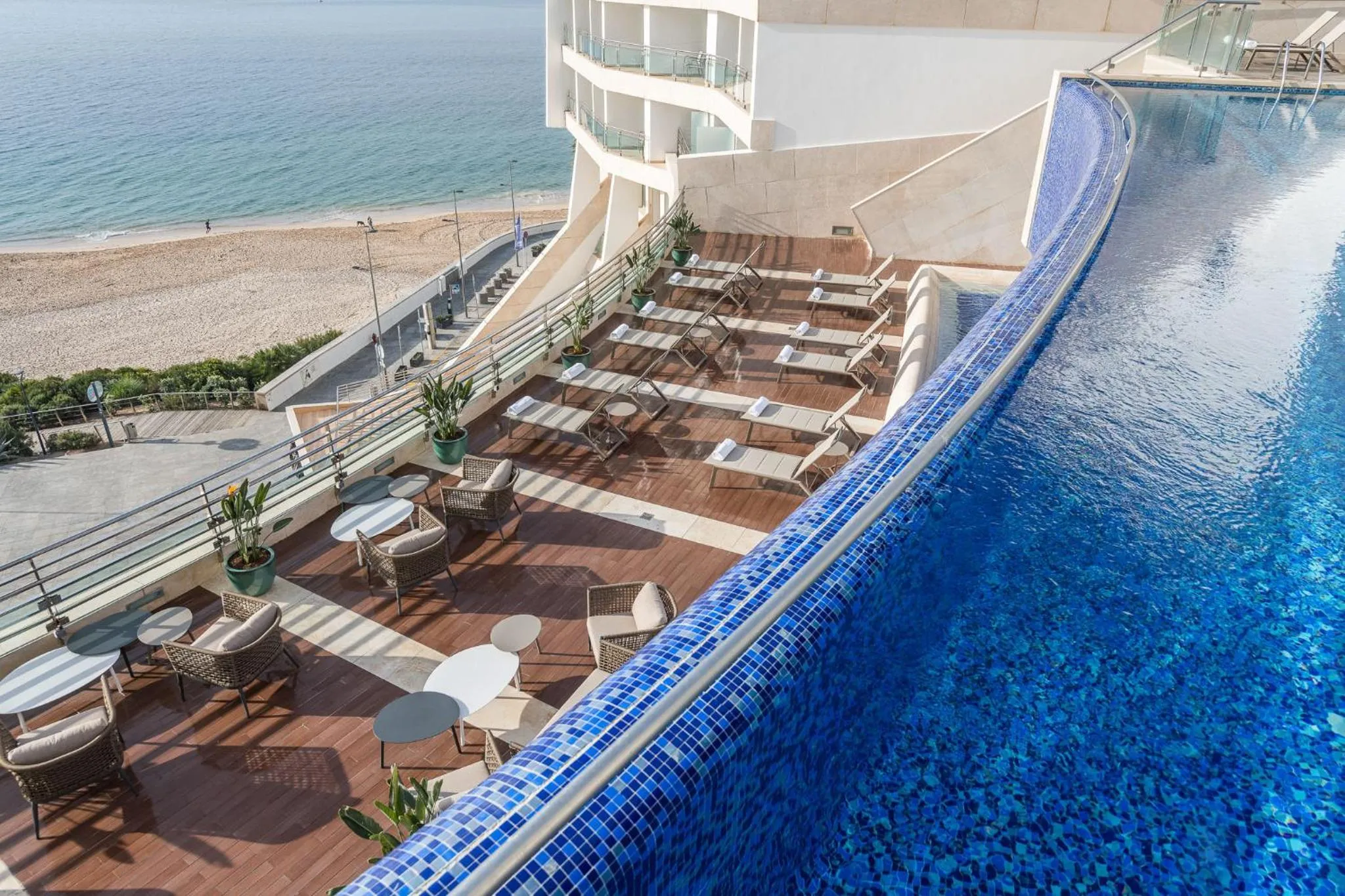 Terrasse avec mobilier de détente et piscine à débordement donnant sur la mer.