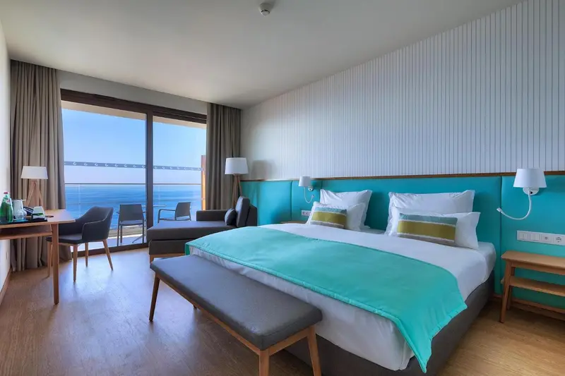 Chambre lumineuse avec un lit double et une vue sur la mer.