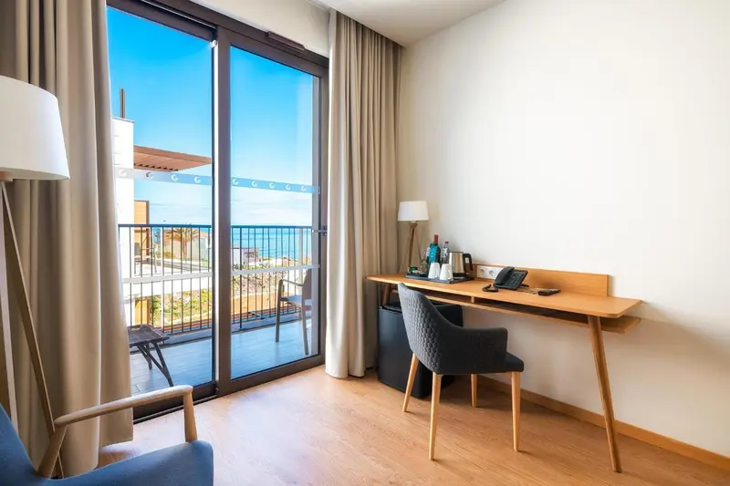 Une chambre lumineuse avec un bureau donnant sur une vue mer.