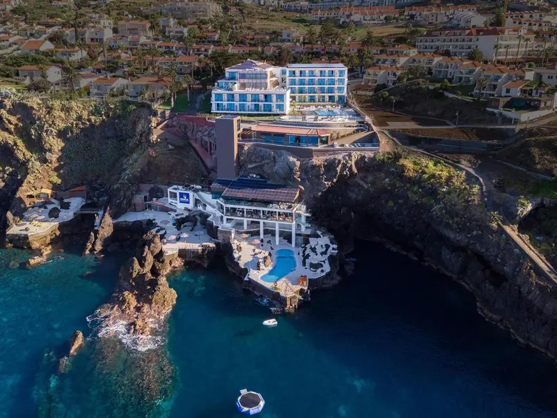 Vue aérienne d'un complexe hôtelier surplombant une crique rocheuse et la mer.