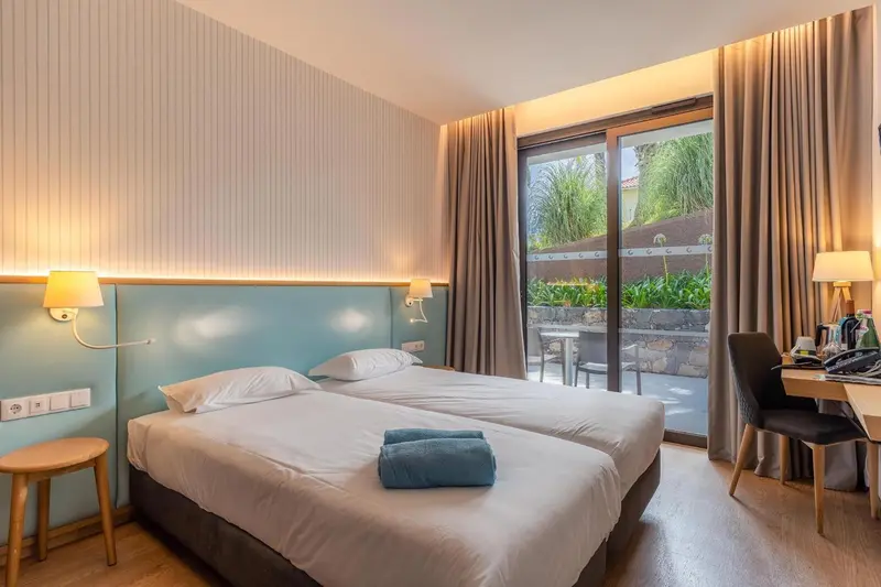 Une chambre lumineuse avec deux lits simples et un accès à une terrasse.