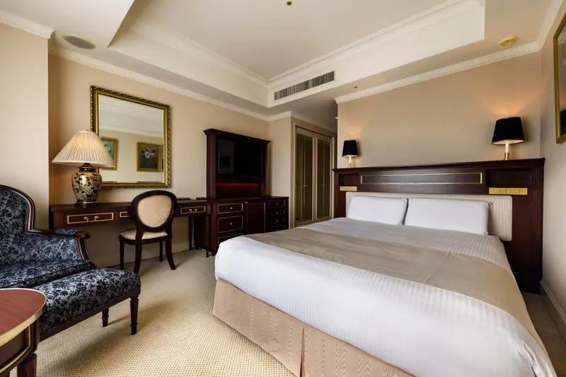 Chambre d'hôtel lumineuse avec un lit double et un coin bureau.