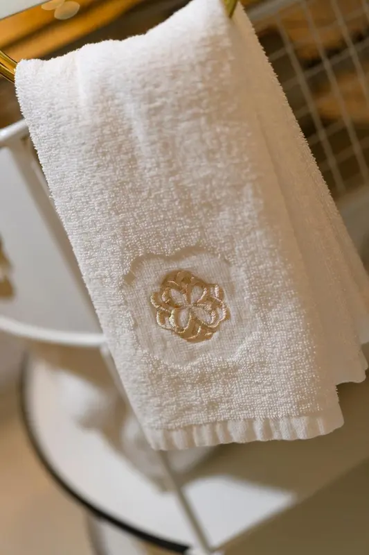 Serviette blanche brodee suspendue dans une salle de bain.