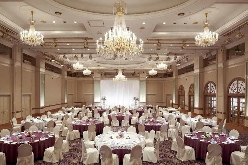 Grande salle de réception avec tables rondes dressées pour un événement.