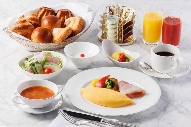 Un plateau de petit-déjeuner avec viennoiseries, fruits, salade et boissons.