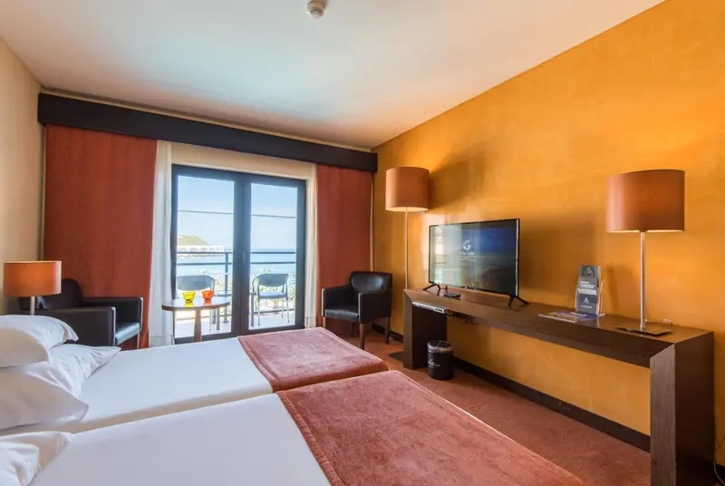 Chambre moderne avec un lit et un accès à un balcon donnant sur la mer.