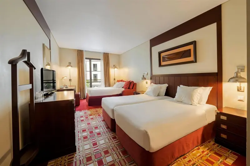Une chambre d'hôtel lumineuse avec deux lits simples et un décor sobre.