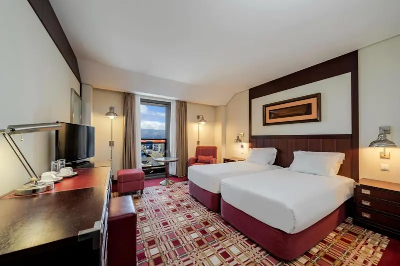 Une chambre d'hôtel avec deux lits simples et un bureau.