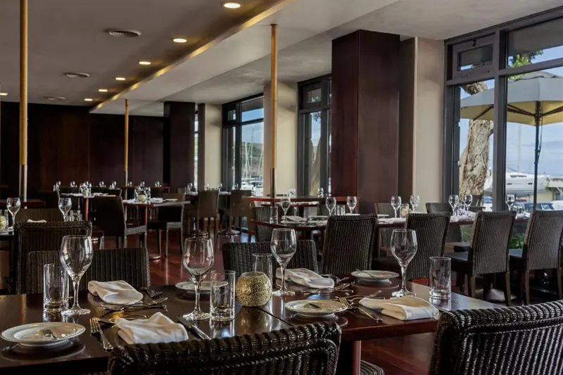 Une salle de restaurant lumineuse avec des tables dressées et de grandes fenêtres.