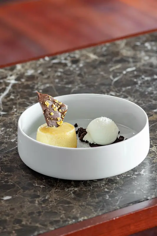 Présentation d'un dessert à base de crème glacée et d'une tuile croustillante.