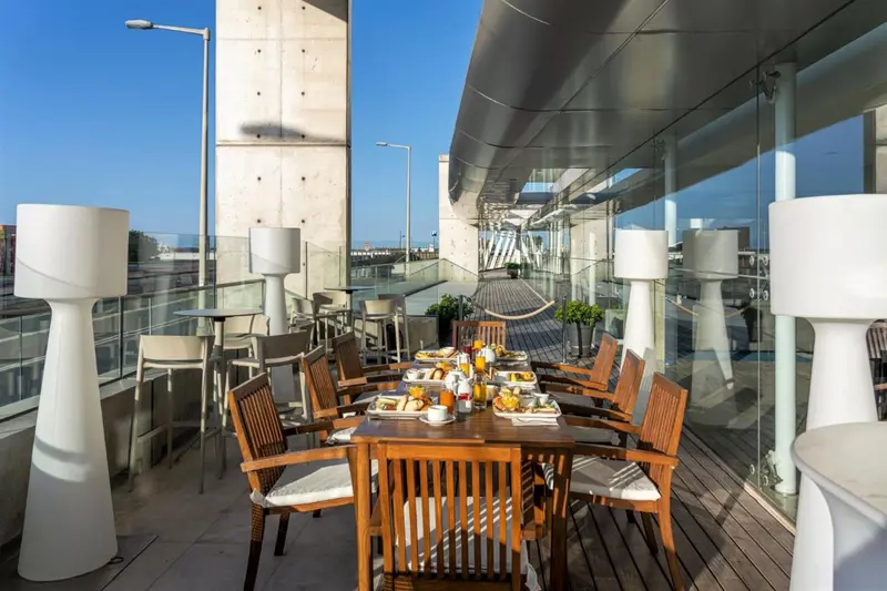 Tables et chaises disposées sur une terrasse avec vue sur la mer.