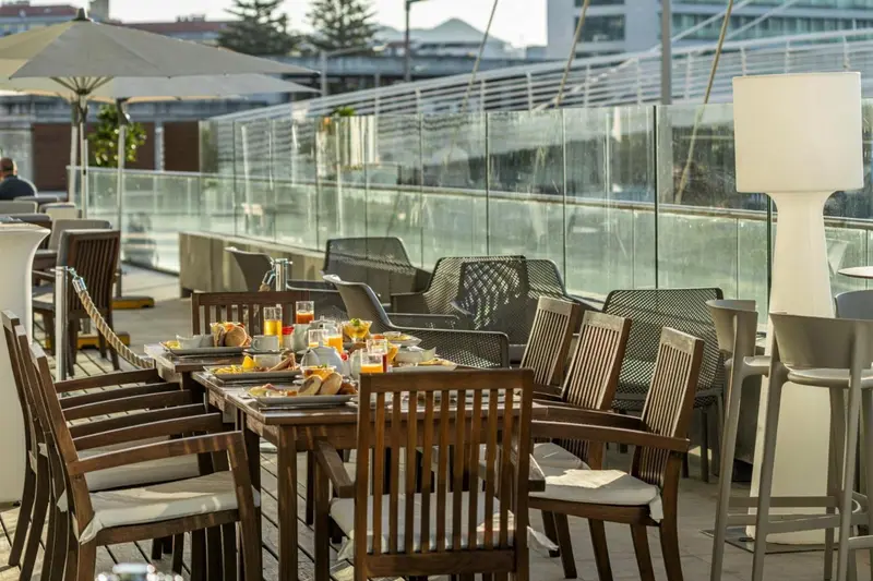Tables dressées pour le petit-déjeuner sur une terrasse ensoleillée.