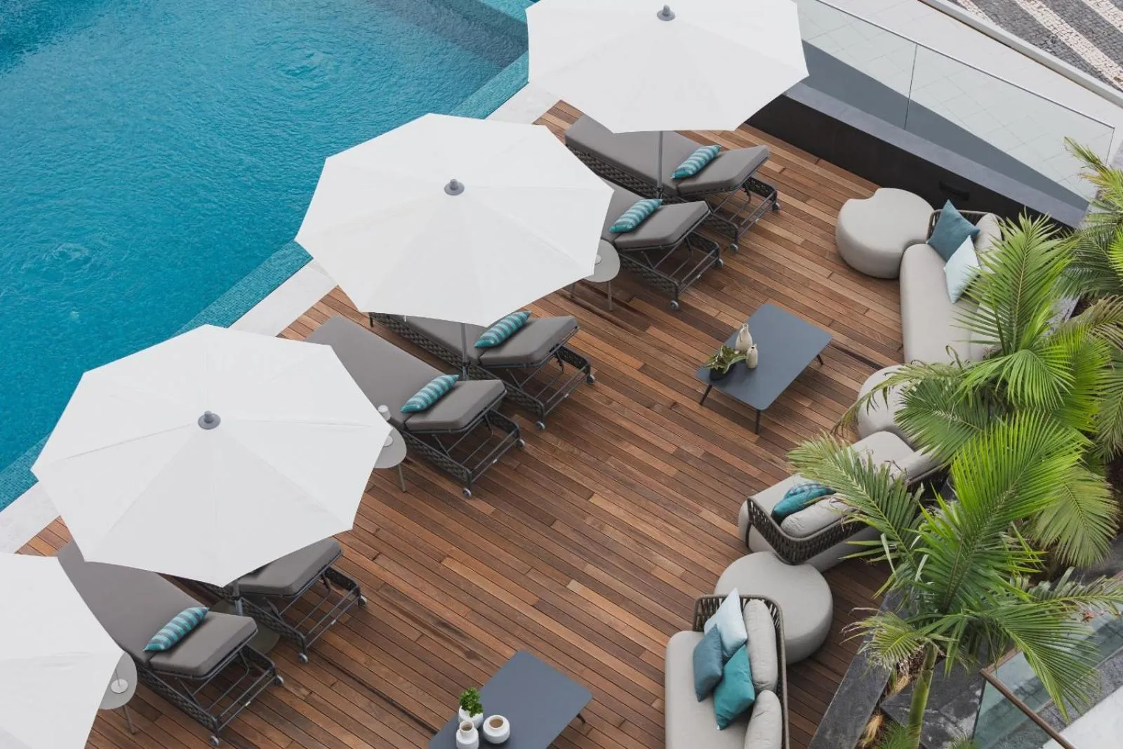 Terrasse avec transats et parasols au bord d'une piscine.