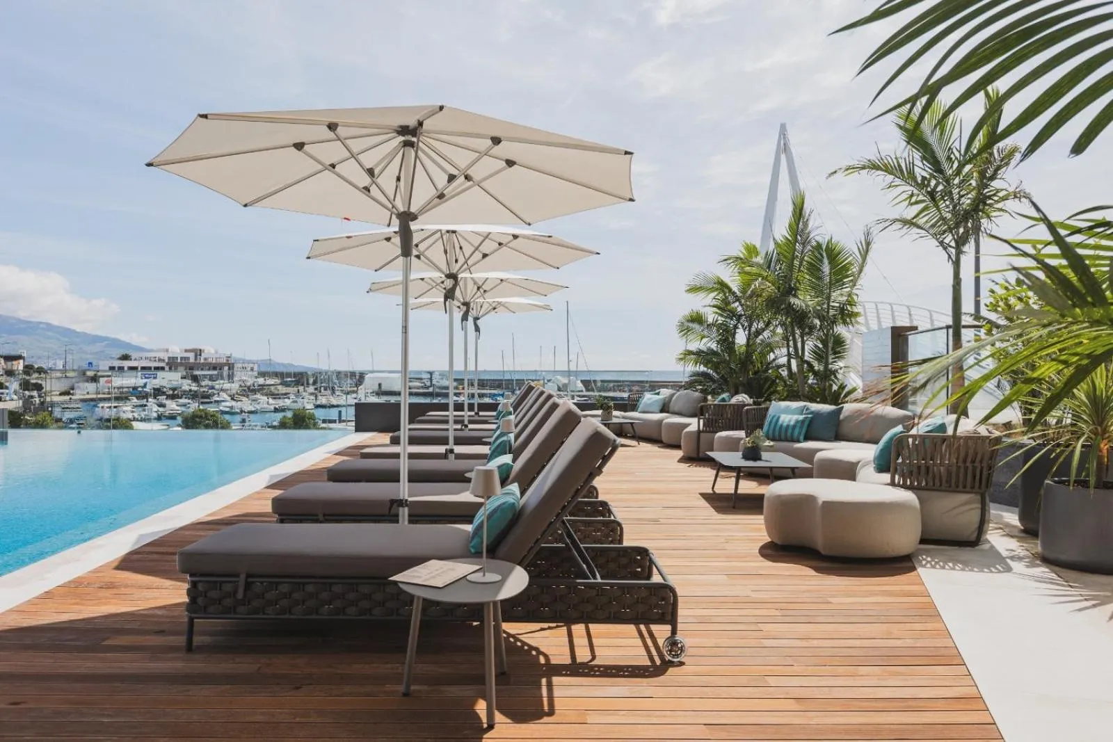 Terrasse avec transats et piscine au bord de l'eau.