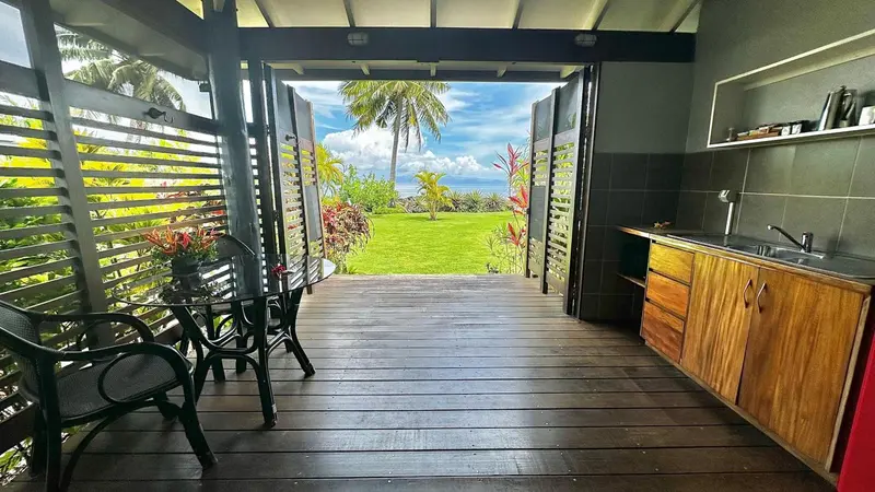 Une cuisine ouverte sur une terrasse en bois avec vue sur un jardin verdoyant.