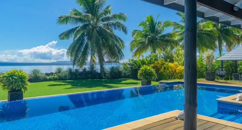 Une piscine à débordement offre une vue sur la mer et la végétation tropicale.