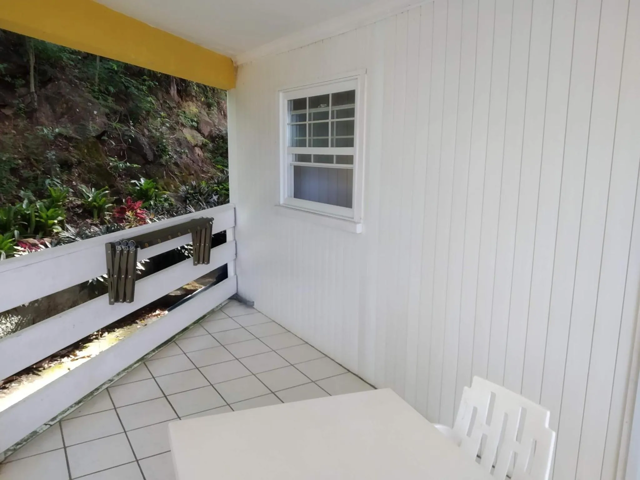 Terrasse carrelée avec table et rambarde blanche.