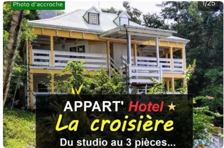 Bâtiment jaune à deux étages avec des balcons et une végétation luxuriante.